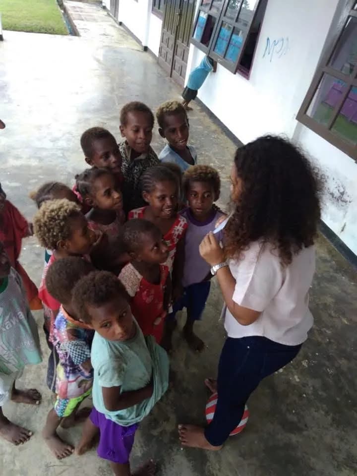 Relawan berinteraksi dengan anak-anak di luar ruangan di komunitas Papua